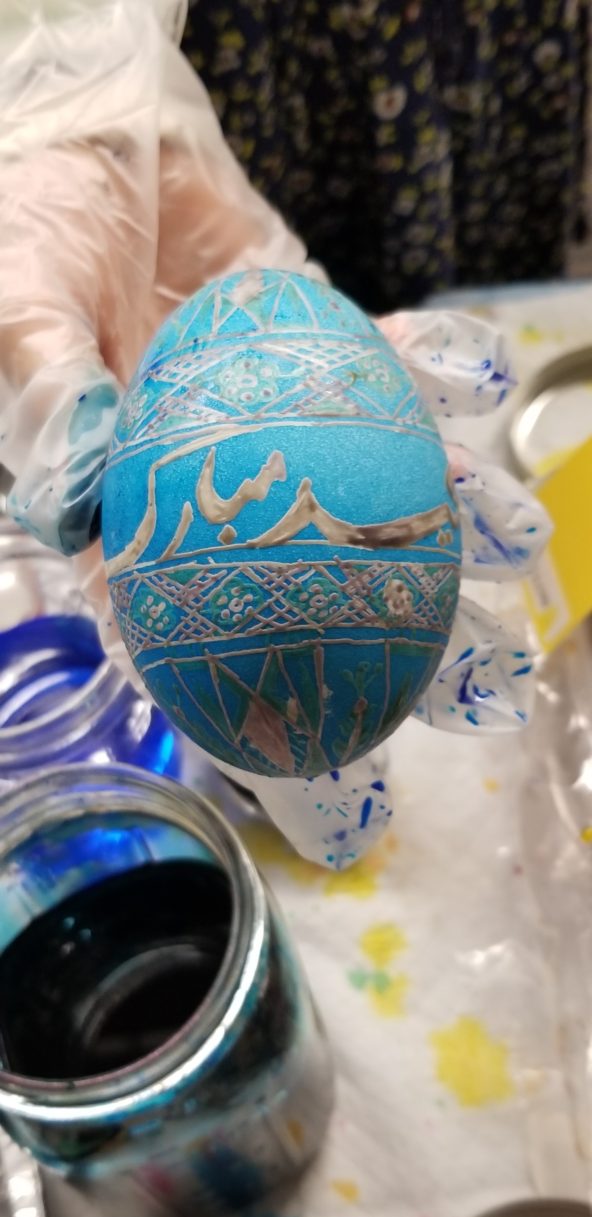 student decorates an egg with Arabic phrase, mubarak