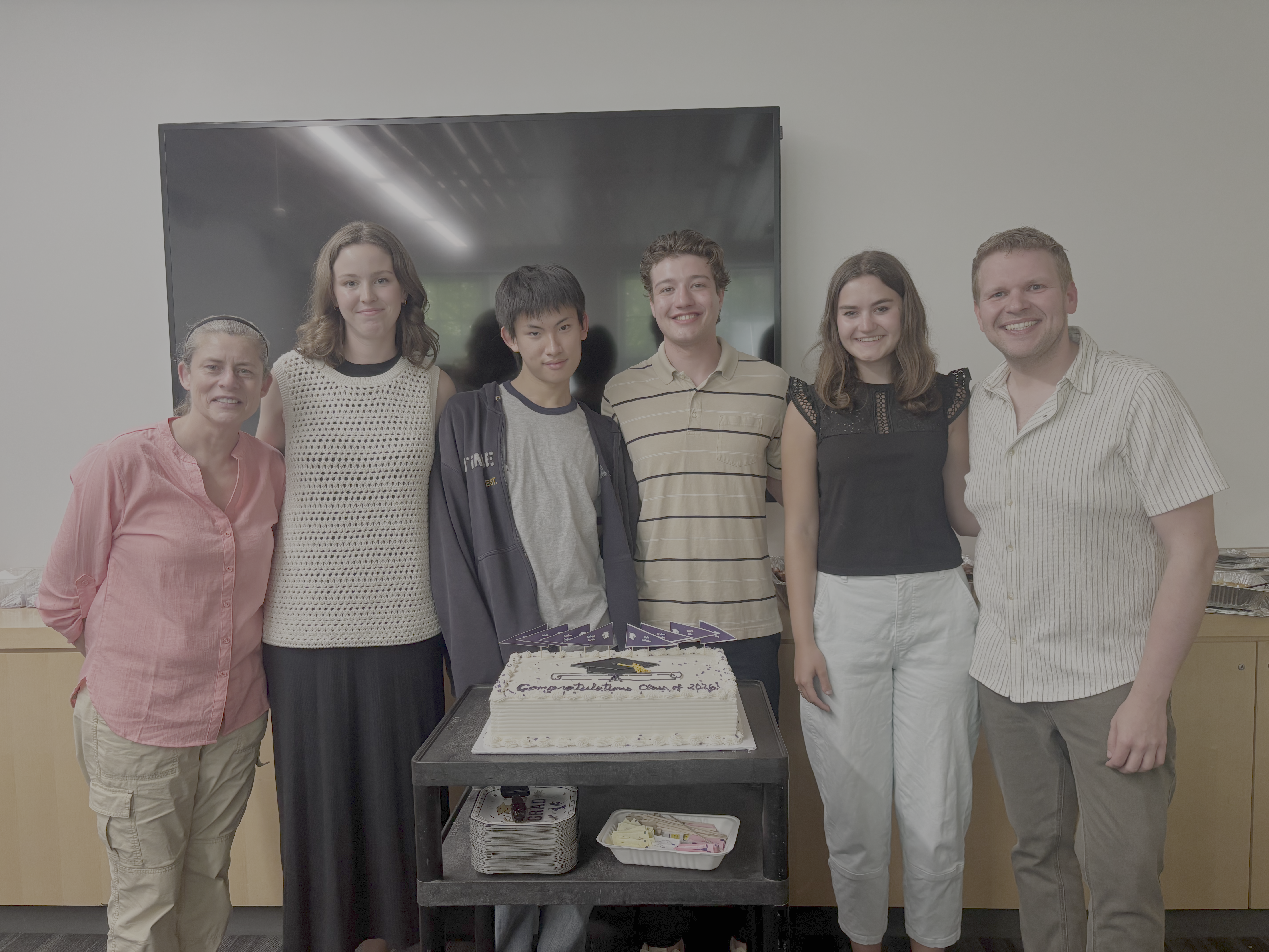 Some graduating seniors pose with the graduation cake flanked by the Department Chair and Director of Undergraduate Studies
